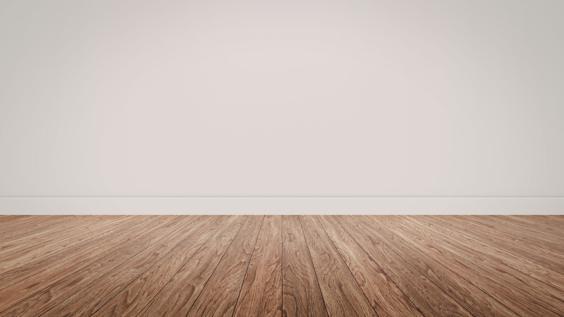 A plain, light-colored wall above dark, wood-grain floorboards.