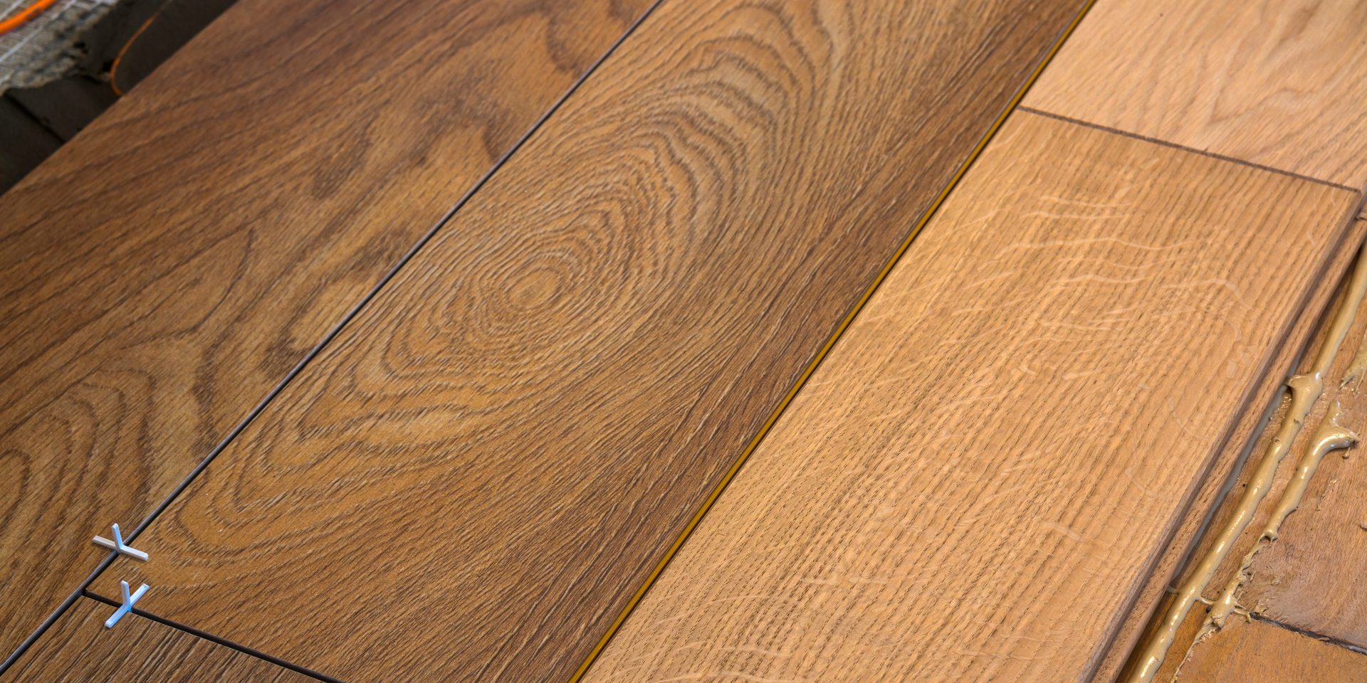 Three wooden floor planks of varying shades—dark walnut, medium brown, and light oak—laid side-by-side.