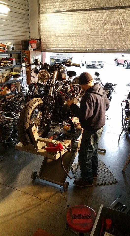 A man is working on a motorcycle in a garage.