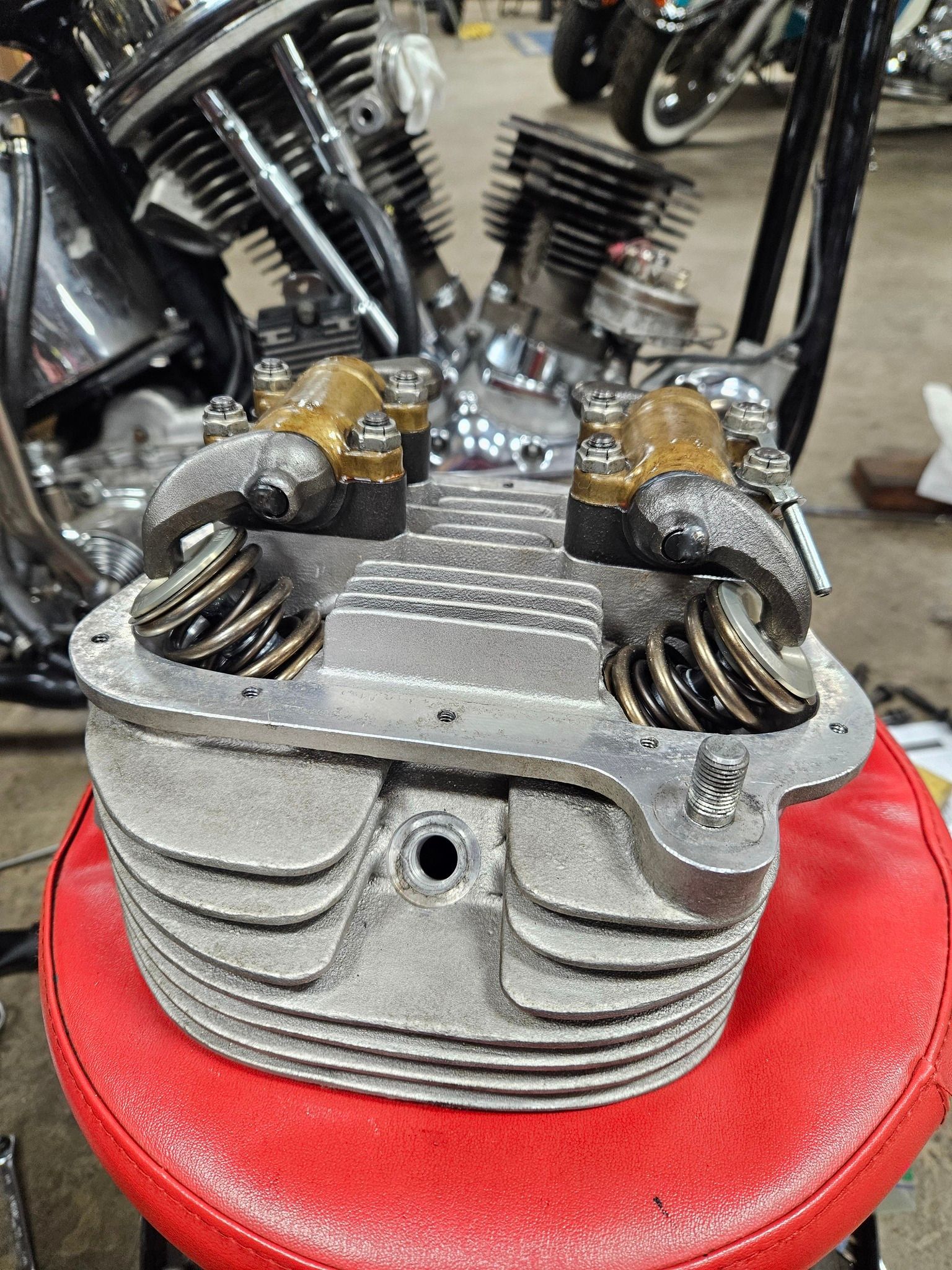 A motorcycle engine head is sitting on top of a red stool.