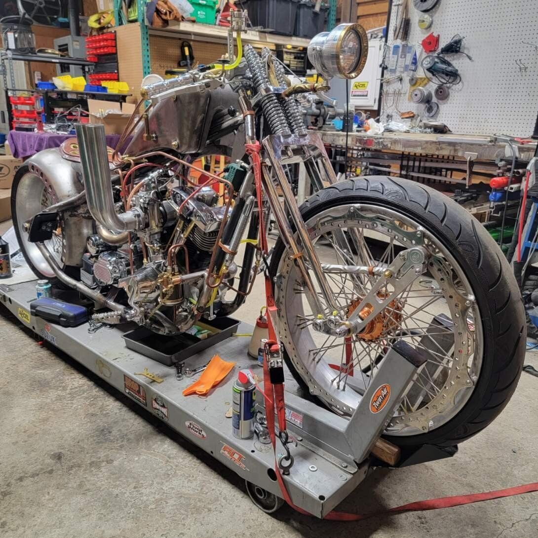 A motorcycle is sitting on a cart in a garage.