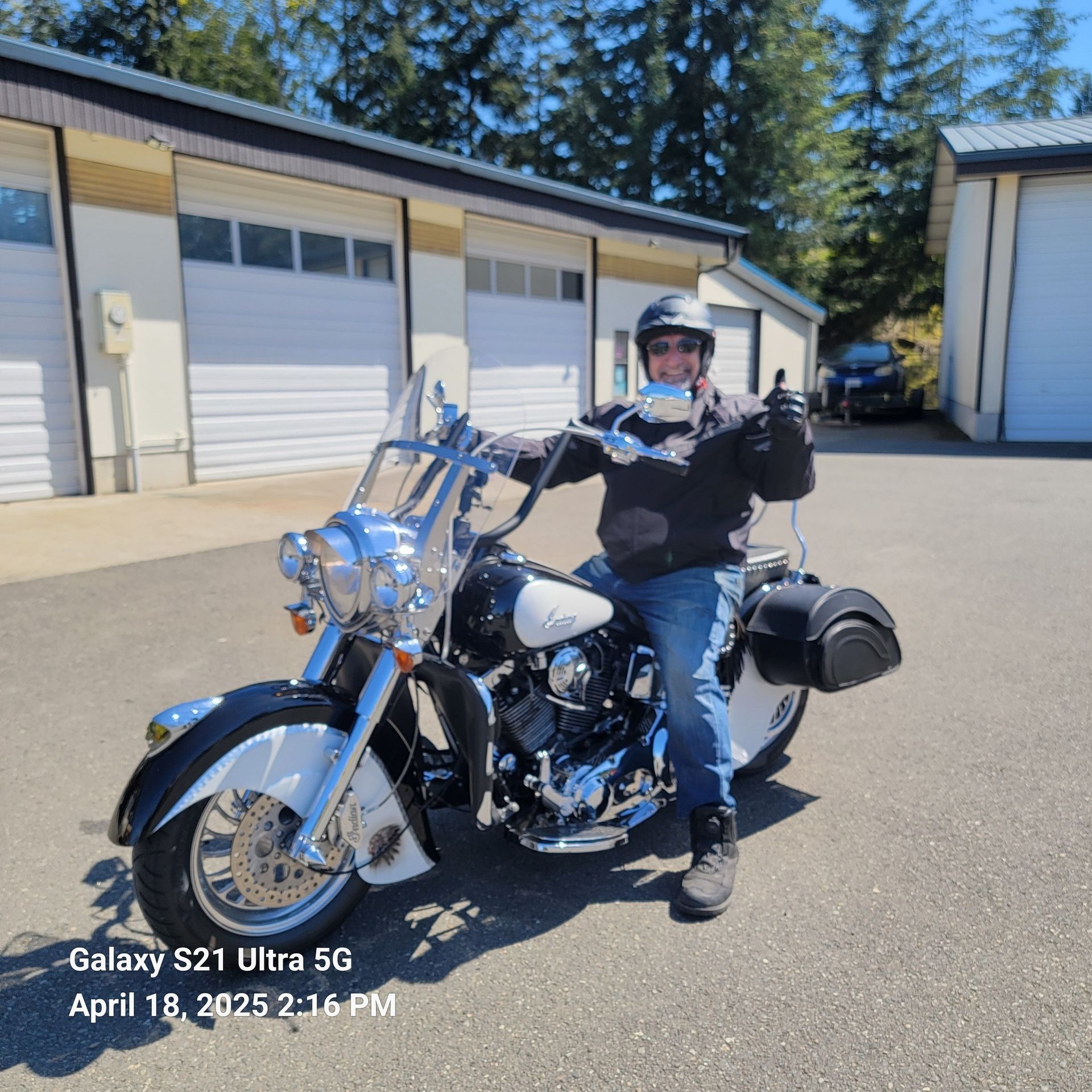 A man is standing next to a motorcycle in a parking lot.