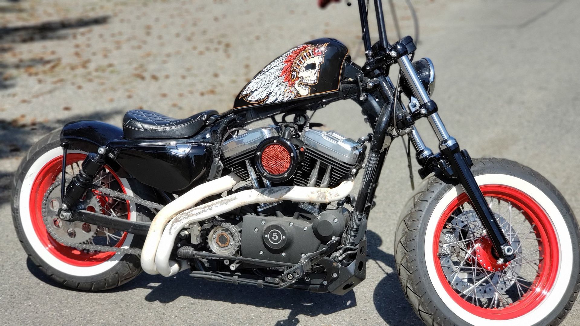 A black and red motorcycle with white tires is parked on the side of the road.