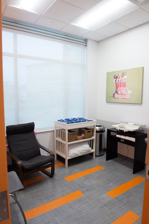 Small office room with chair, baby changing table, infant scale, and picture of a baby.