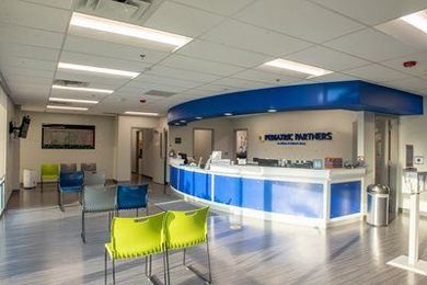 Bright office reception desk with blue and white counters and waiting chairs in a clean lobby at our Olathe location.
