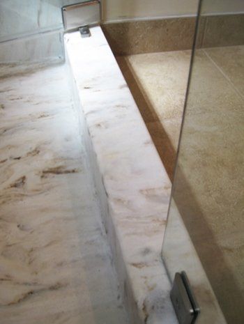 A bathroom with a marble counter top and a glass shower door.