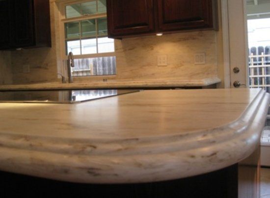 A kitchen with a marble counter top and dark cabinets