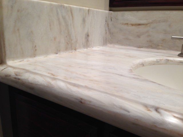 A bathroom sink with a marble counter top and a faucet.