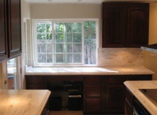 A kitchen with brown cabinets and a large window.