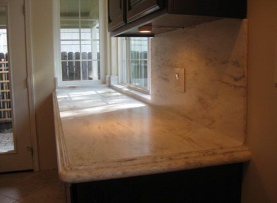A kitchen with a marble counter top and a window