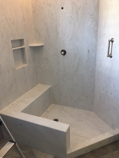 A bathroom with a walk in shower and a bench.