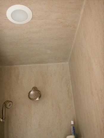 A bathroom with a shower head and a light on the ceiling.