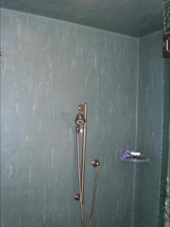 A bathroom with a shower head and a shelf.
