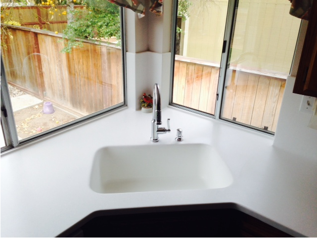 A kitchen sink with a window and a fence in the background