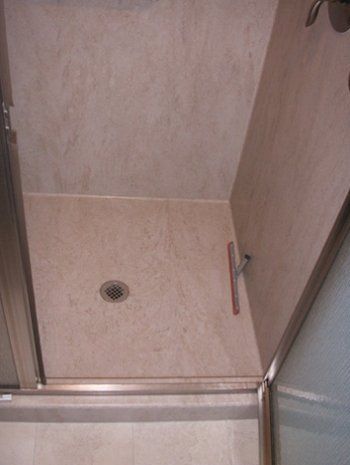 A bathroom with a walk in shower and a drain.