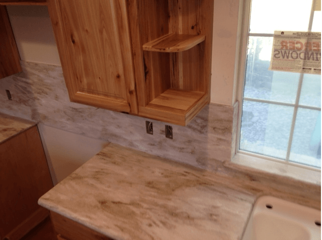 A kitchen with wooden cabinets and marble counter tops.