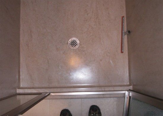 A bathroom with a shower stall and a drain on the floor