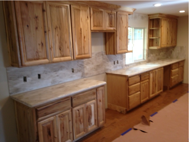 A kitchen with wooden cabinets and marble counter tops.