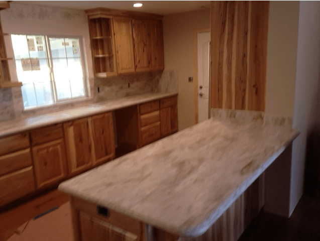 A kitchen with wooden cabinets and a large island in the middle.
