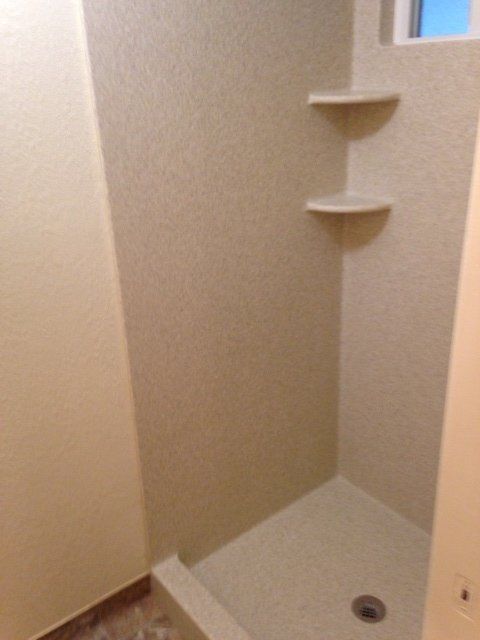 A shower stall with shelves and a window in a bathroom.