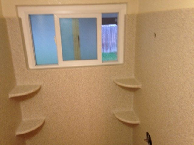 A bathroom with shelves and a window in the corner