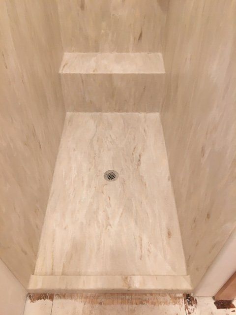 A bathroom with a marble shower stall and shelves.