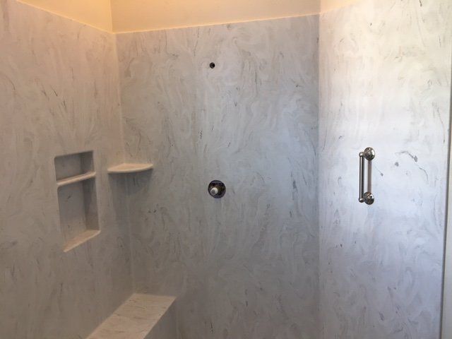 A bathroom with a walk in shower and a bench.