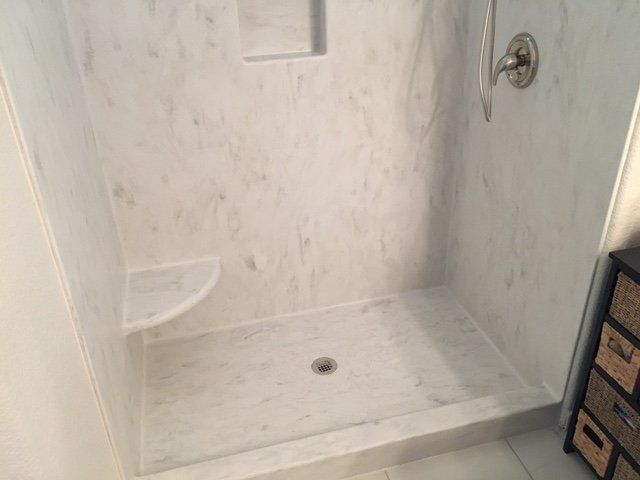 A bathroom with a walk in shower and a dresser.