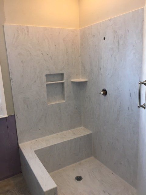 A shower with a bench and shelves in a bathroom.