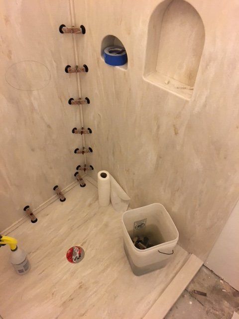 A bathroom with a bucket and a roll of paper towels on the floor.