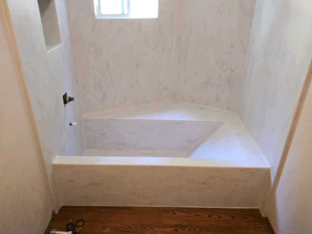 A bathroom with a bathtub and a window.