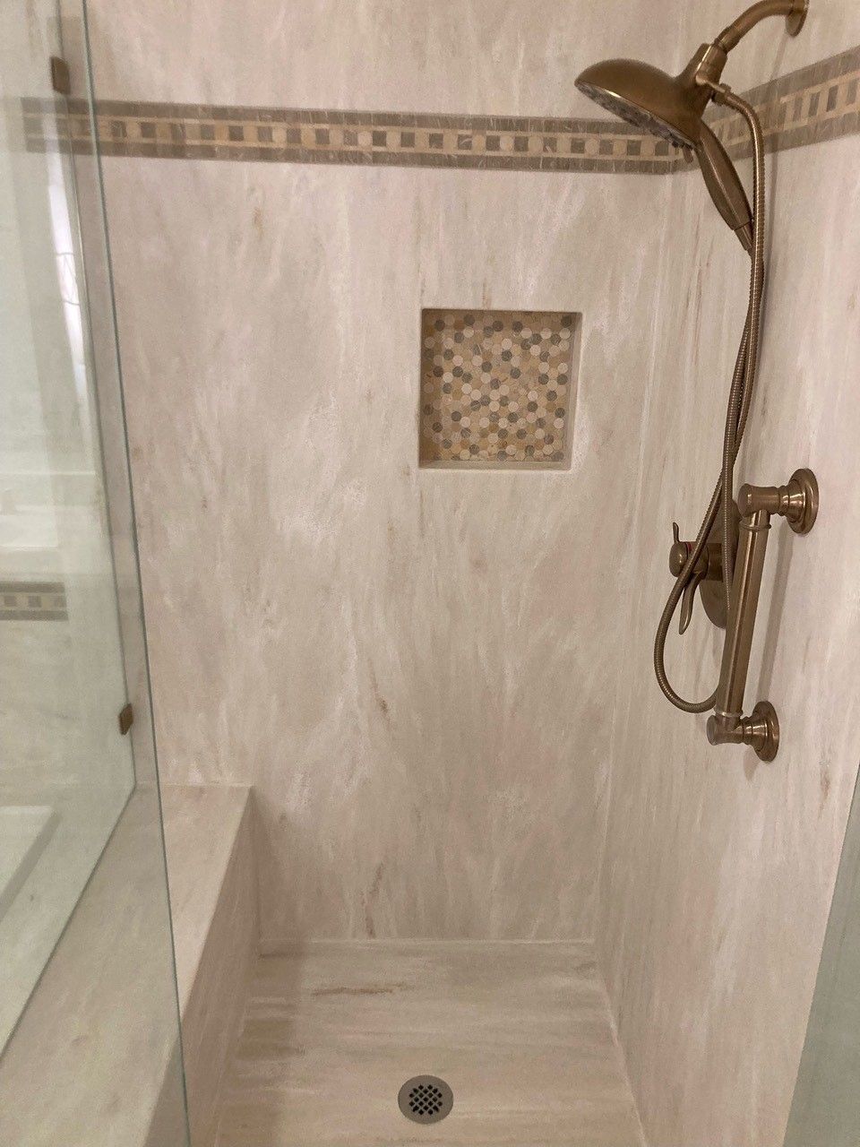 A shower with a shower head and a glass door in a bathroom.