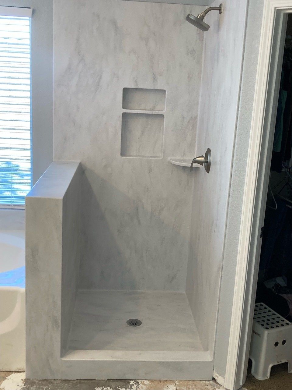 A shower stall in a bathroom with a window and a shower head.
