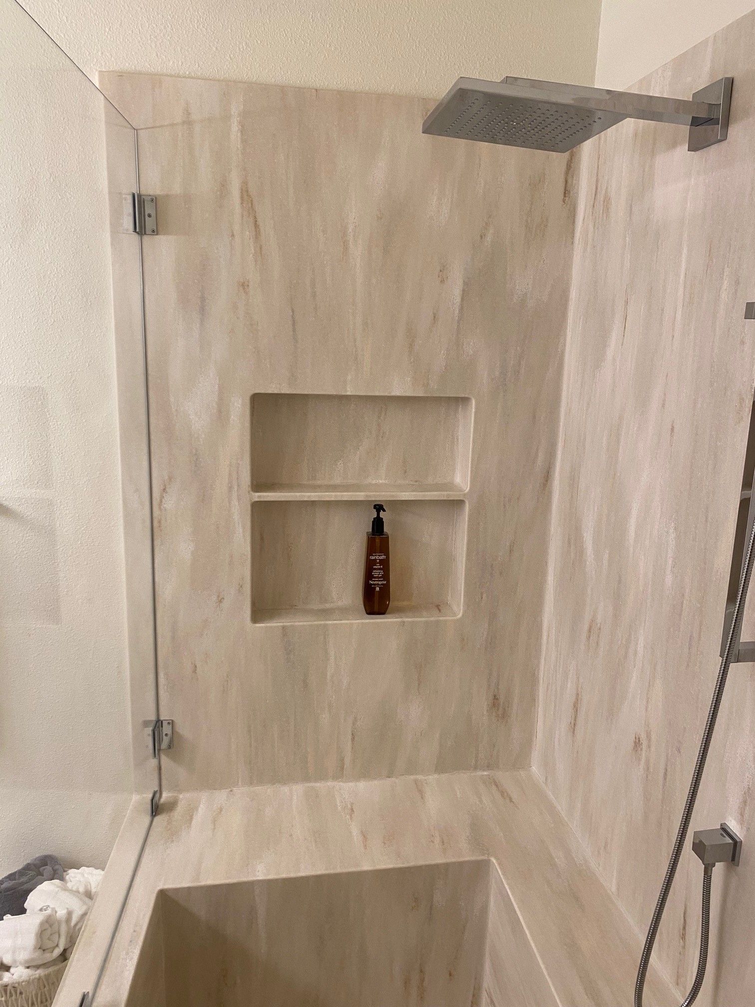 A bathroom with a tub , shower , and soap dispenser.