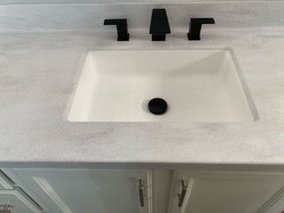 A bathroom sink with a black faucet and drain.