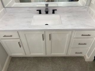 A bathroom vanity with a sink , mirror and drawers.