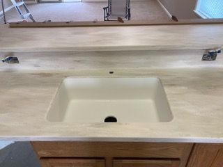 A bathroom sink with a wooden counter top and a mirror.