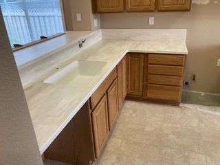 A kitchen with a sink , cabinets , and a window.