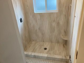 A bathroom with a walk in shower and a window.
