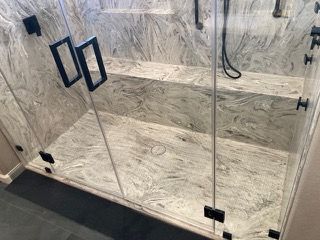 A bathroom with a walk in shower and a glass door.