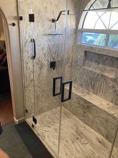 A bathroom with a walk in shower and a window.