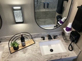 A bathroom with a sink , mirror , and dryer.