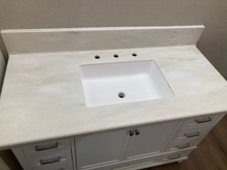 A bathroom vanity with a white sink and a white counter top.