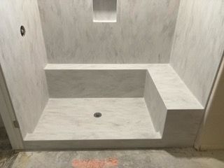 A bathroom with a shower stall and a bench.