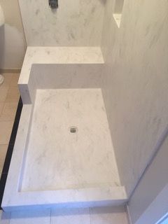 A shower stall with a bench in a bathroom.