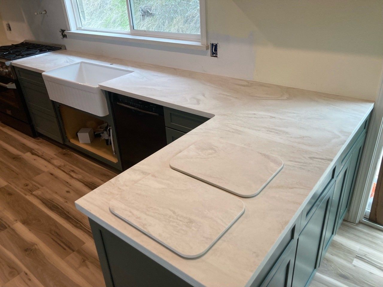 A kitchen with two sinks , a stove , and a window.