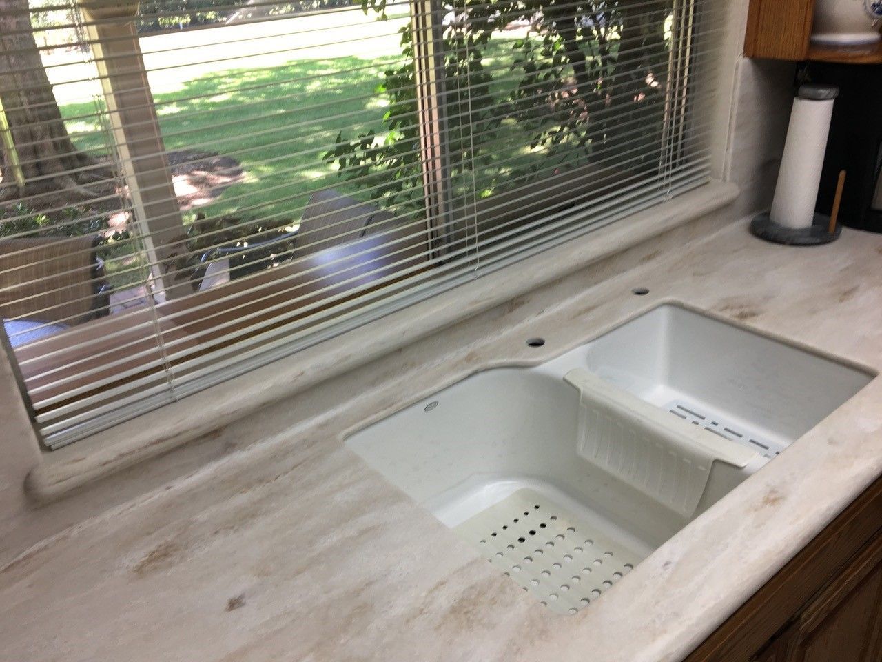 A kitchen sink under a window with blinds on it