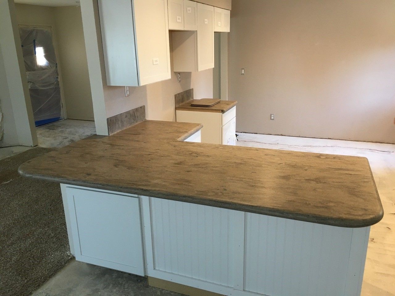 A kitchen with a brown counter top and white cabinets.