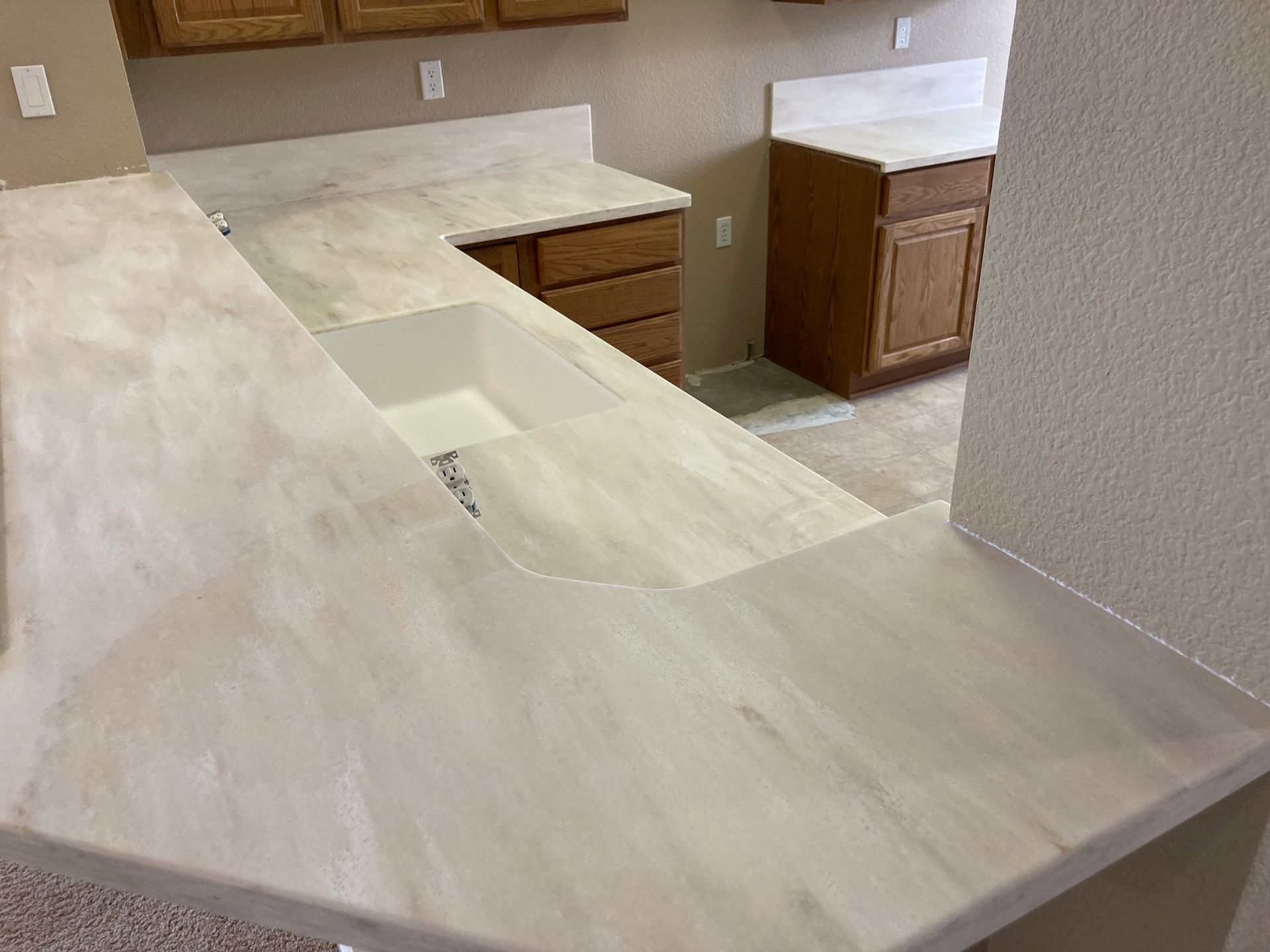 A kitchen with white counter tops and wooden cabinets.