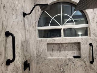 A bathroom with a window and a shower head.